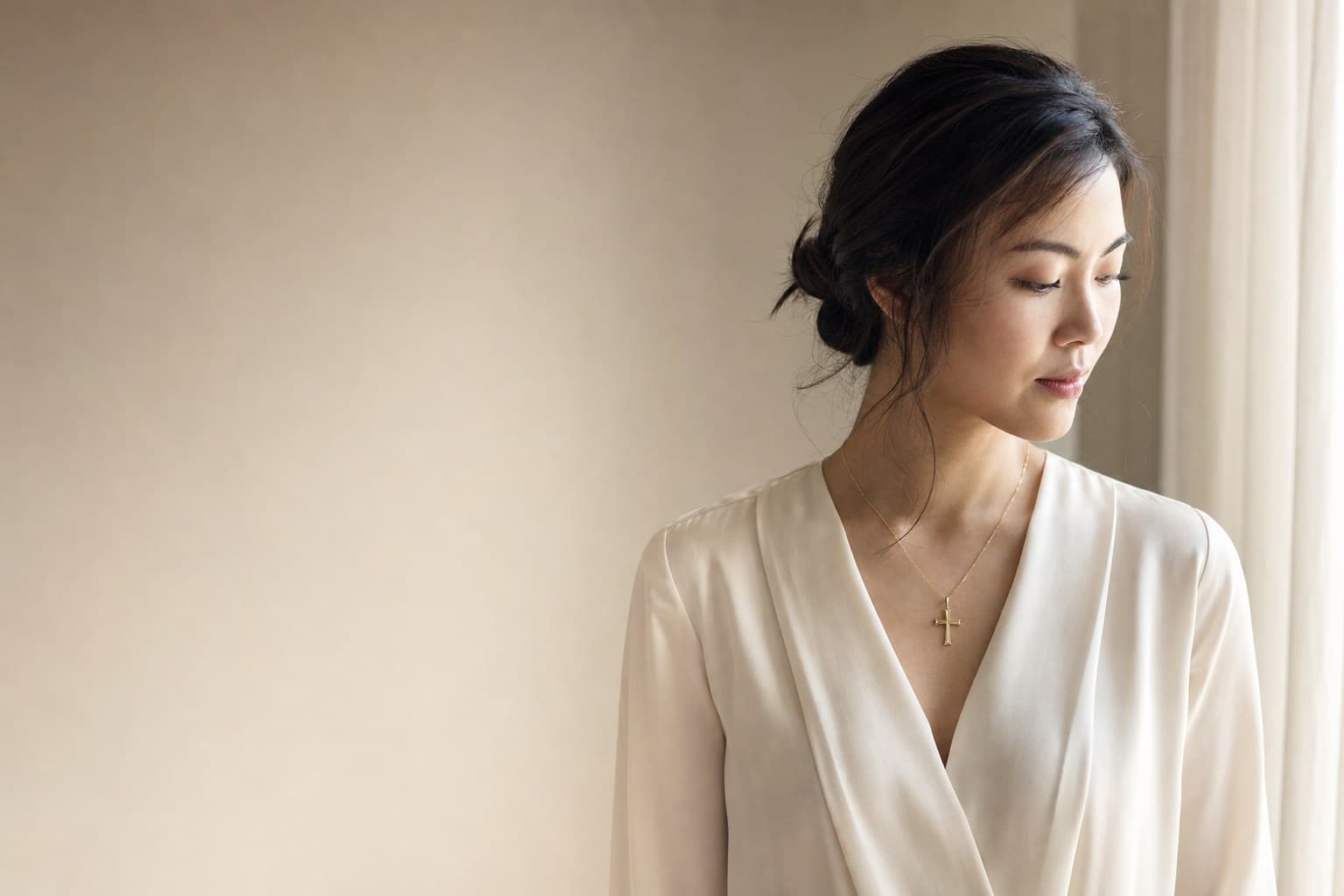 A woman wearing the Kainos cross in 18K gold on a fine gold chain, resting below the collarbone